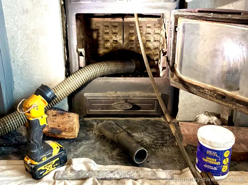 Professional chimney cleaning and wood burner sweep in progress — vacuum hose, sweep rods and Arctic Hayes smoke cartridges, experienced NACS registered sweep, Allchimney Sweeps, Essex