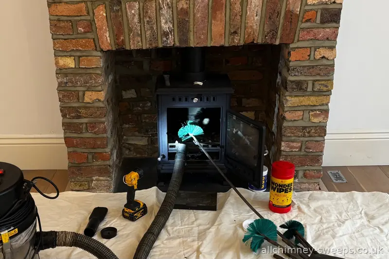 NACS registered chimney sweep in progress — 5 inch brush and flexi rods through 125mm stove liner, professional equipment on dust sheets, Allchimney Sweeps, Harold Hill